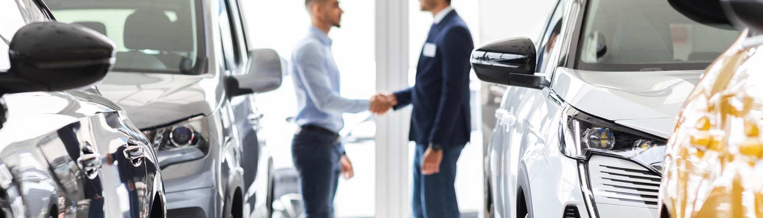 image of two business people shaking hands inside of a car dealership.