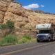 Side view of an RV driving down a desert road